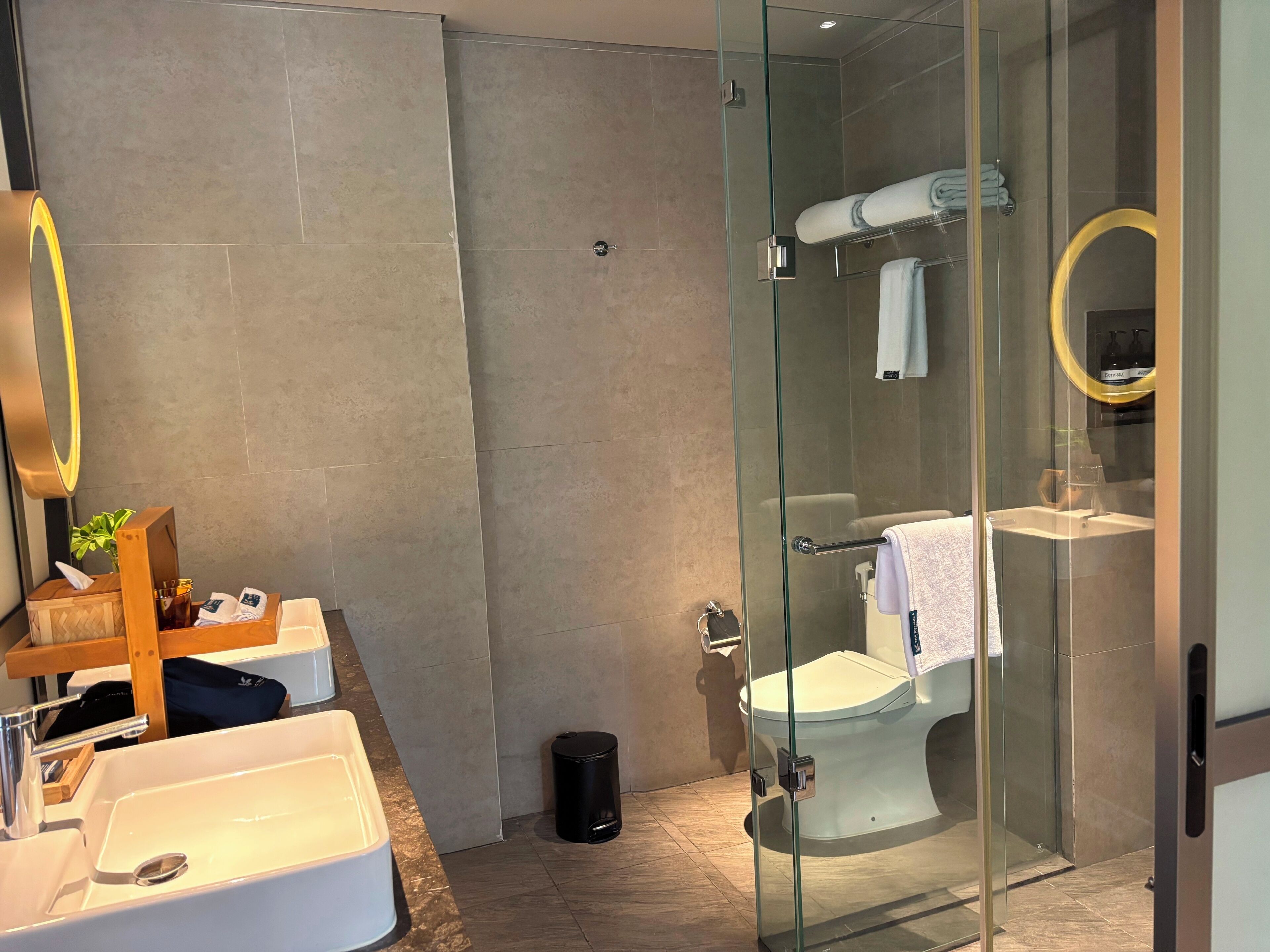 Un bagno moderno con cabina doccia in vetro, lavandino bianco e specchio con cornice dorata.