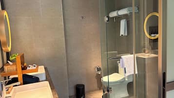 Un bagno moderno con cabina doccia in vetro, lavandino bianco e specchio con cornice dorata.