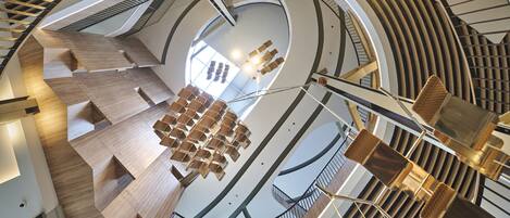A modern interior with a circular staircase, wooden flooring, and hanging light fixtures.