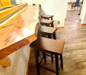 A wooden bar with three stools and a wooden table. - No Cleaning Fee, Stay One Stay All (Lewellen)