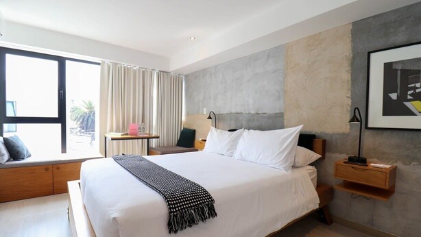 A modern hotel room with a large bed, a bedside table, a lamp, and a view of the outdoors. - w*| Spacious Loft w/AC in Barranco (Barranco)