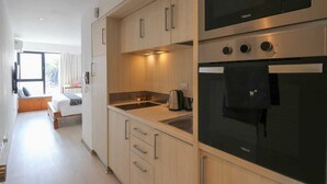 A modern kitchen with wooden cabinets, a built-in oven, and a microwave. - w*| Spacious Loft w/AC in Barranco (Barranco)