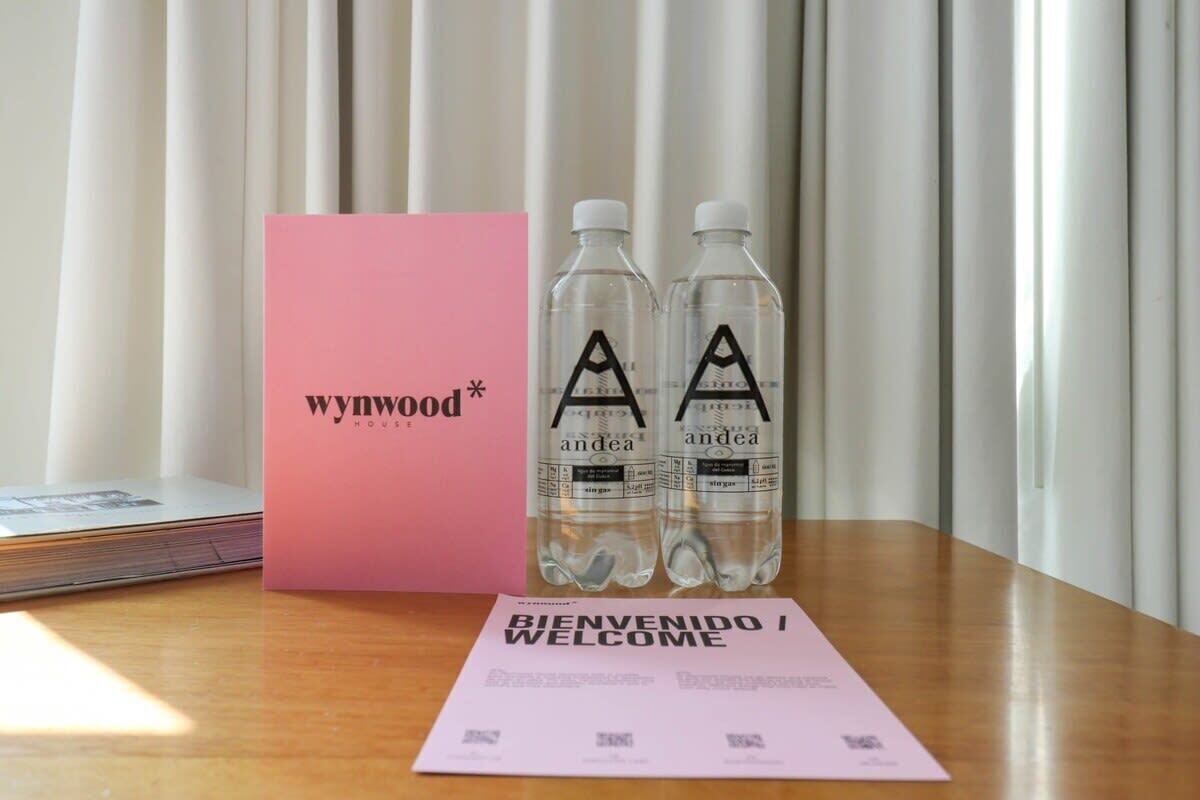 A wooden table with a pink box labeled 'wynwood', two water bottles, and a welcome card.