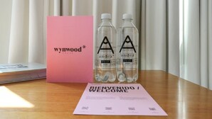 A wooden table with a pink box labeled 'wynwood', two water bottles, and a welcome card. - w*| Spacious Loft w/AC in Barranco (Barranco)