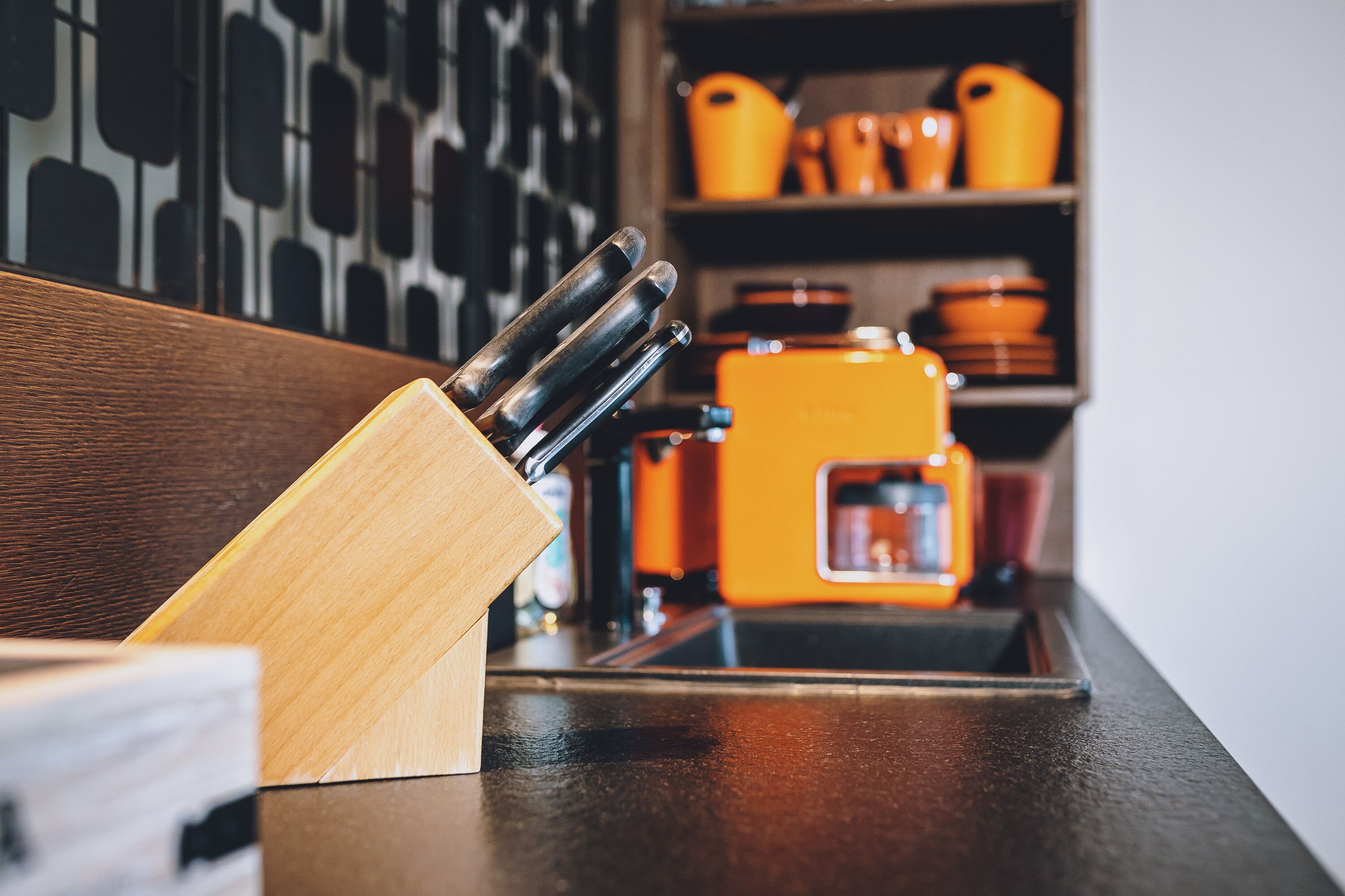 A kitchen counter with a wooden knife block and a coffee machine.