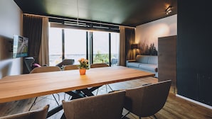 Un espace repas moderne avec une table en bois, six chaises et une plante en pot.
