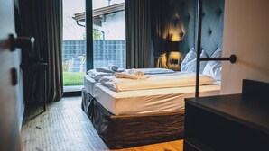 Une chambre d’hôtel avec un lit, un plancher en bois, une fenêtre avec des rideaux et une vue sur l’extérieur.