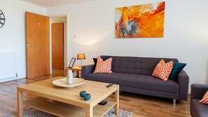 A modern living room with a grey sofa, wooden coffee table, and a painting on the wall. - ByEvo 5 Brabloch GLA Apartment  (Paisley)