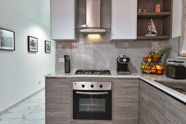 A modern kitchen with a built-in oven, a gas stove, and a coffee maker. - A Bed of Roses (Żebbuġ)