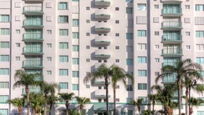 A multi-story hotel with balconies, palm trees in front, and a clear sky. - Le Montcalm 102 STR-01921 (Sunny Isles Beach)