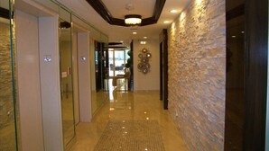 A hotel lobby with a polished floor, a stone accent wall, and a chandelier. - Le Montcalm 102 STR-01921 (Sunny Isles Beach)