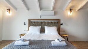 A neatly made bed with white and gray linens, two bedside tables with lamps, and a wooden headboard.