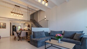 A modern living room with a grey sectional sofa, a wooden coffee table, and a staircase leading to an upper level.
