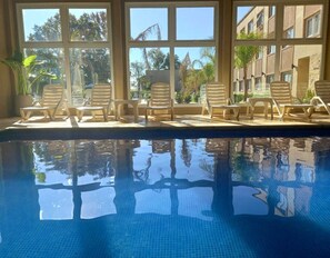 Una piscina cubierta, una piscina al aire libre de temporada, sombrillas