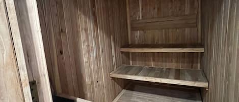 A wooden interior with a sloped ceiling, a built-in bench, and a shelf.