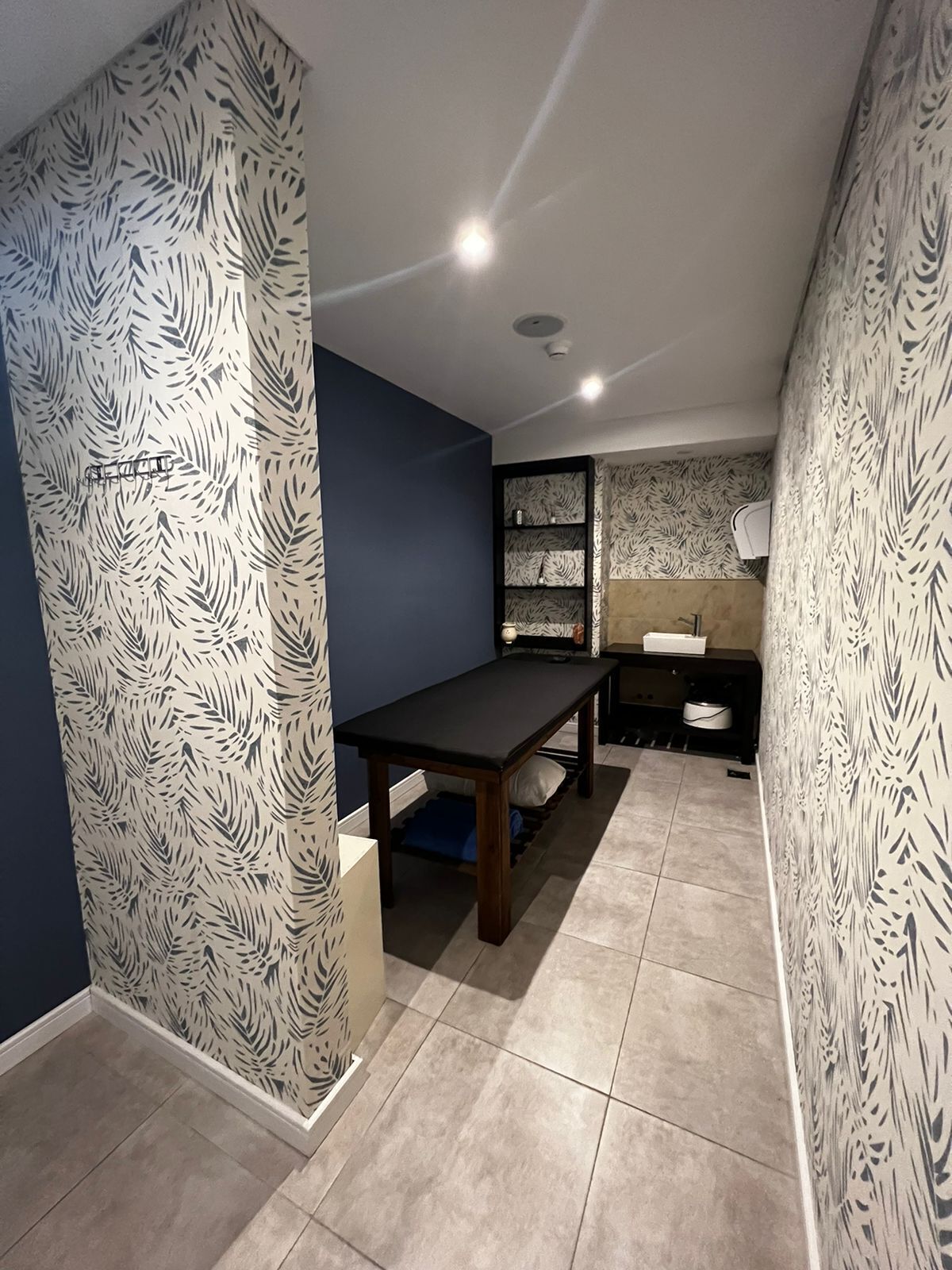 Una cocina moderna con una pared azul oscuro, un papel tapiz estampado y una mesa de madera.