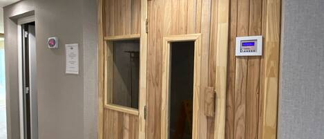 A hallway with a wooden wardrobe, a digital thermostat, and a sign on the wall.