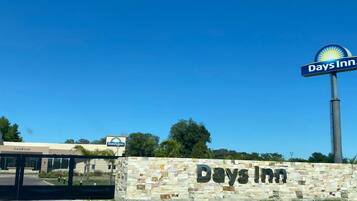 A Days Inn sign with a stone wall and a clear blue sky in the background.