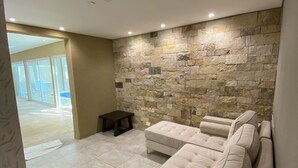 A modern living room with a stone wall, a beige sectional sofa, and a small table. - Days Inn by Wyndham Zarate (Zárate)