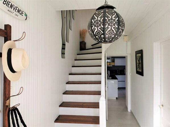 A staircase with white walls and wooden steps leading to a kitchen area.