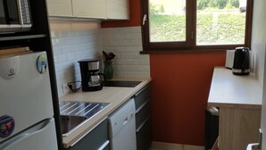 A compact kitchen with white cabinets, a built-in microwave, a coffee maker, and a window with a view of greenery. - APARTMENT LA TOUSSUIRE, 3 ROOMS 6/8 PEOPLE (La Toussuire)
