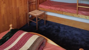 A bunk bed room with a wooden headboard, a chair, and a poster on the wall. - APARTMENT LA TOUSSUIRE, 3 ROOMS 6/8 PEOPLE (La Toussuire)