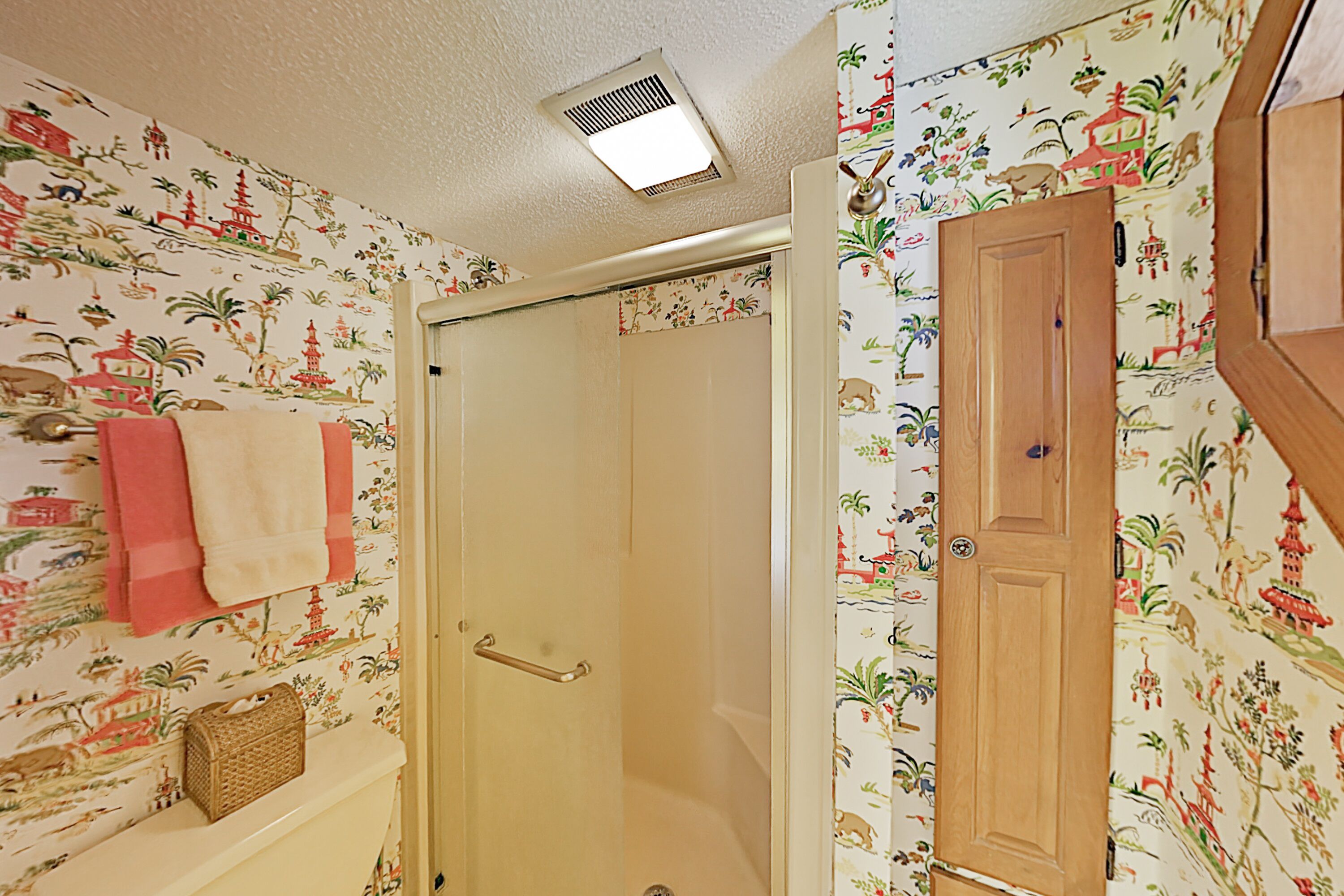 Un baño con ducha, un perchero con toallas y una puerta de madera.