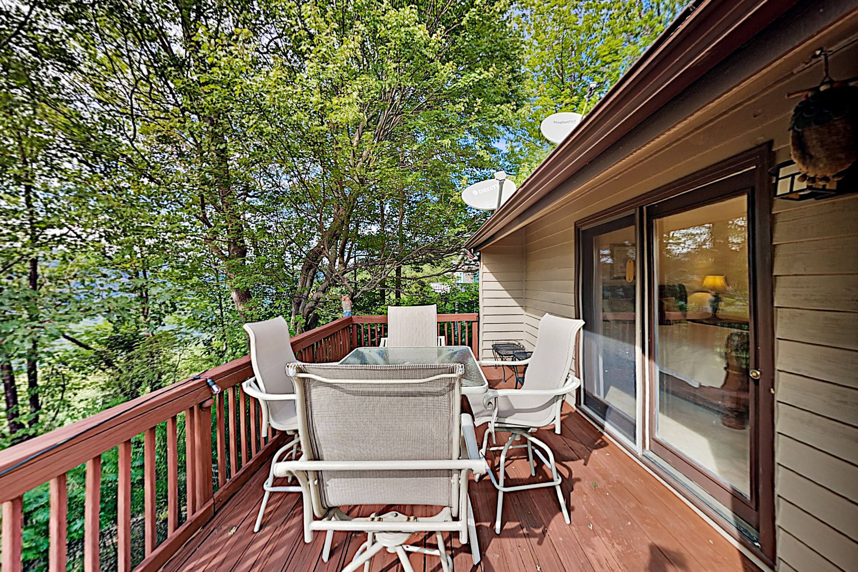 A wooden deck with outdoor furniture and a glass door leading to a room.