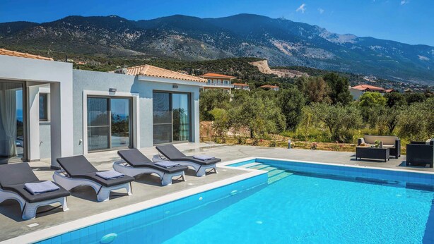 A modern pool area with lounge chairs and a view of mountains.