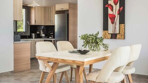 A modern kitchen with wooden cabinets, a stainless steel refrigerator, and a dining area with a white table and chairs.