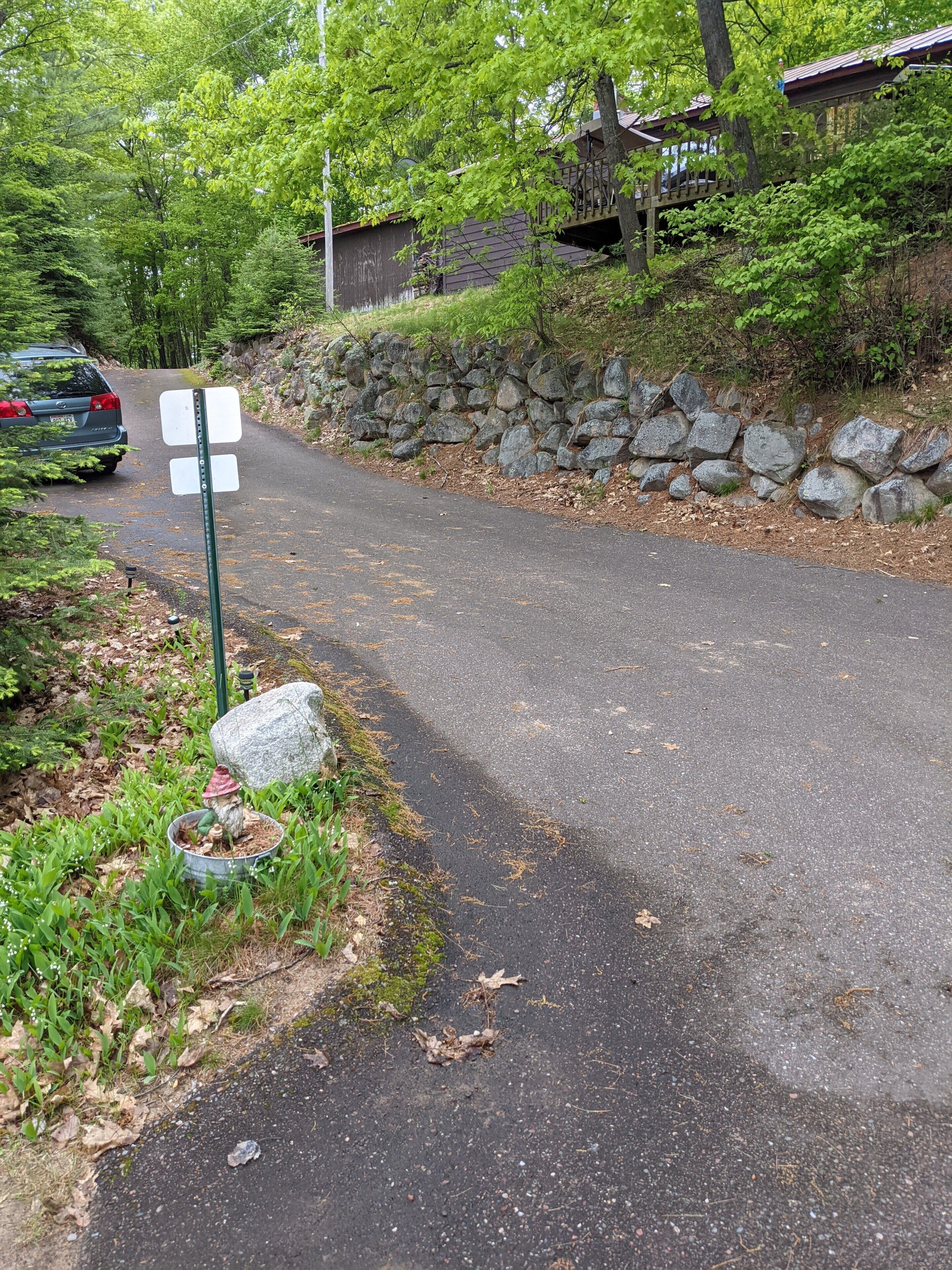 A paved path with a stone wall on one side and a wooden structure in the background.