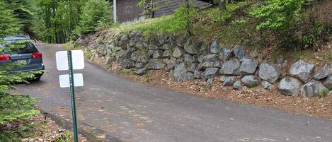 A paved path with a stone wall on one side and a wooden structure in the background.
