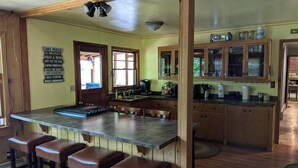 A kitchen with a central island, wooden cabinets, and a bar stool area.