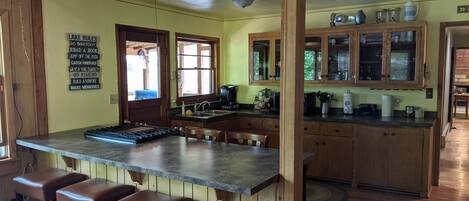Una cocina con isla central, armarios de madera y una zona con taburetes de bar.