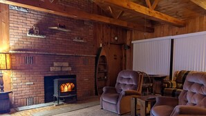 A cozy room with a brick fireplace, wooden beams, and comfortable seating.