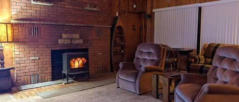 A cozy room with a brick fireplace, wooden beams, and comfortable seating.