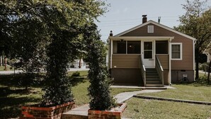 Ein kleines, eingeschossiges Haus mit einer Veranda und einer Treppe, die zum Eingang führt.