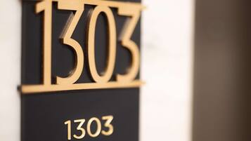 A black and gold house number sign with the number 1303.