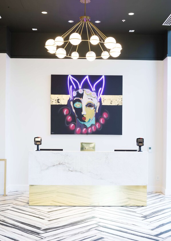 A reception area with a marble counter, a modern chandelier, and a neon art piece on the wall. - The Kelly Birmingham, Tapestry Collection By Hilton (Birmingham)