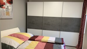 A bed with a colorful quilt and a white headboard. - Newly renovated apartment 65 m2 (Nordhausen)