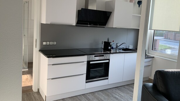 A modern kitchen with white cabinetry, a black countertop, and an oven. - Newly renovated apartment 65 m2 (Nordhausen)