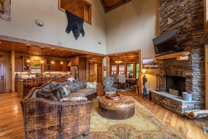 A spacious living area with a stone fireplace, a large sofa, and a dining area with wooden furniture.