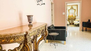 Una habitación con una mesa de mármol, un sofá negro y una mesita redonda.