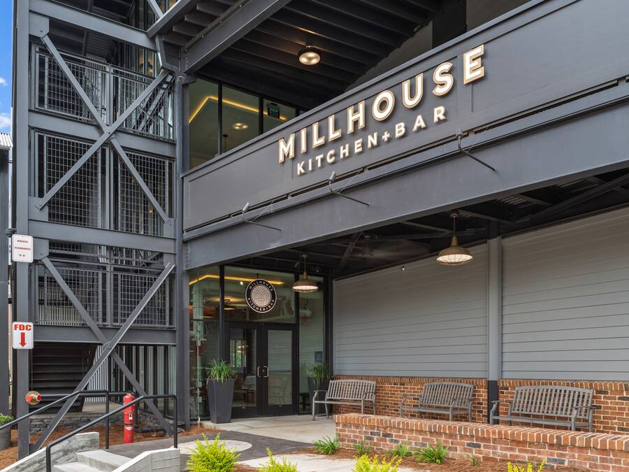 A modern building with a sign reading "Millhouse Kitchen+Bar".