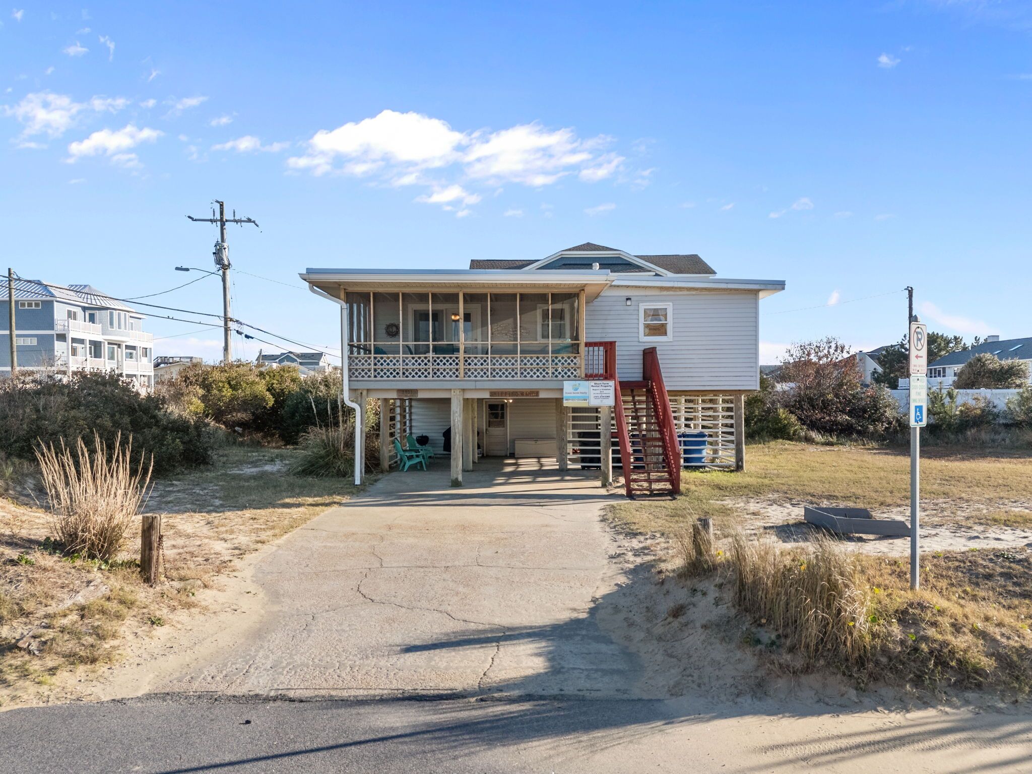 A two-story house with a balcony, a front porch, and a driveway leading to the entrance.