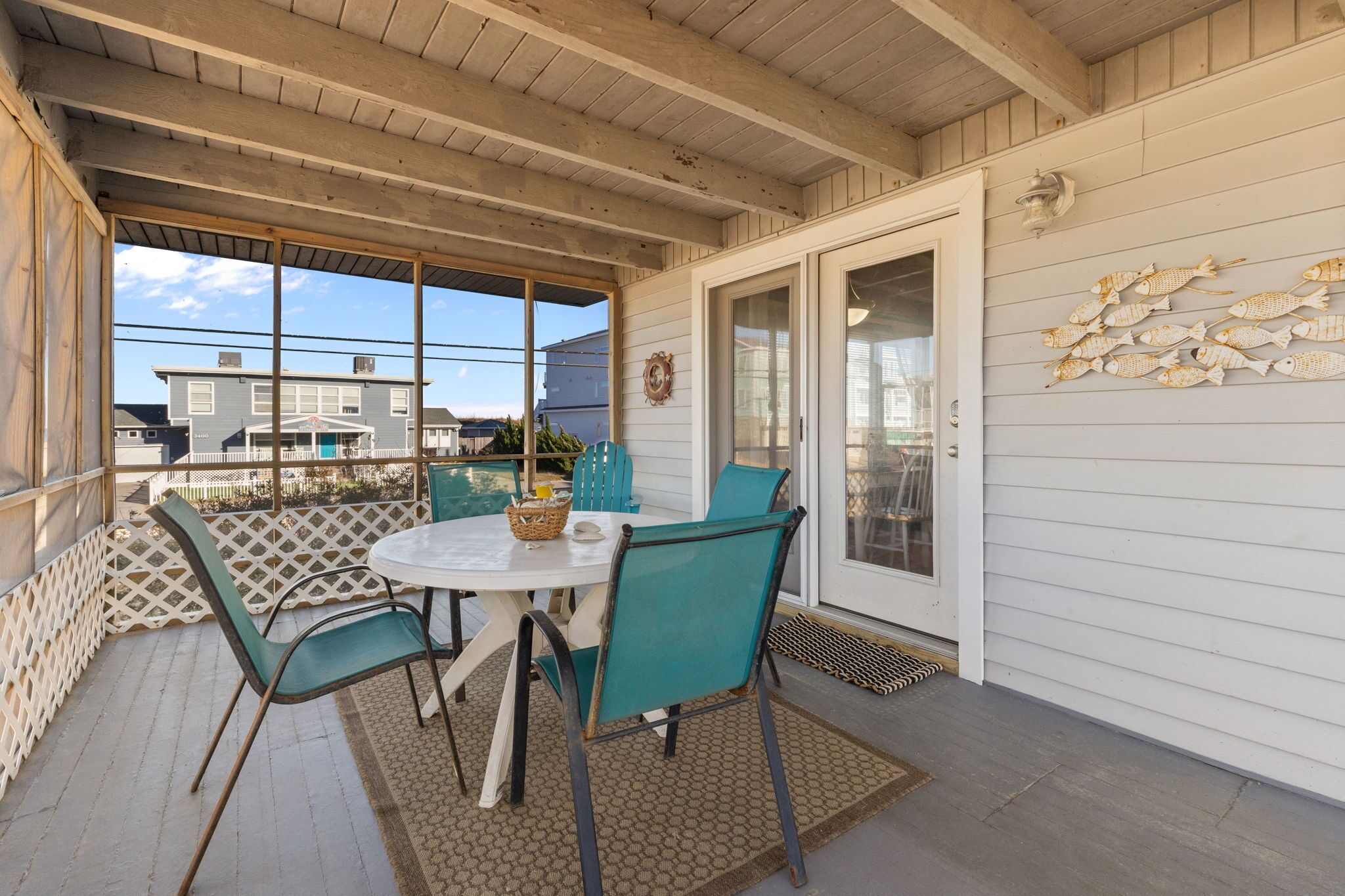 A covered patio with a table and chairs, a decorative fish wall, and a view of neighboring houses.
