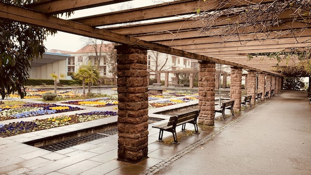 A covered walkway with stone pillars, benches, and flower beds. - Superior-apartment Near Stuttgart, Garden & Sauna (Kornwestheim)