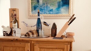 A wooden cabinet with a painting above it, a bottle, a piggy bank, and a basket. - Superior-apartment Near Stuttgart, Garden & Sauna (Kornwestheim)