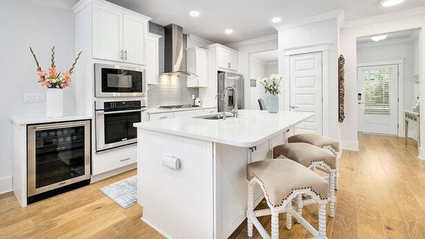 A modern kitchen with white cabinetry, a central island, and a built-in oven.