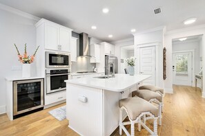 A modern kitchen with white cabinetry, a central island, and a built-in oven.